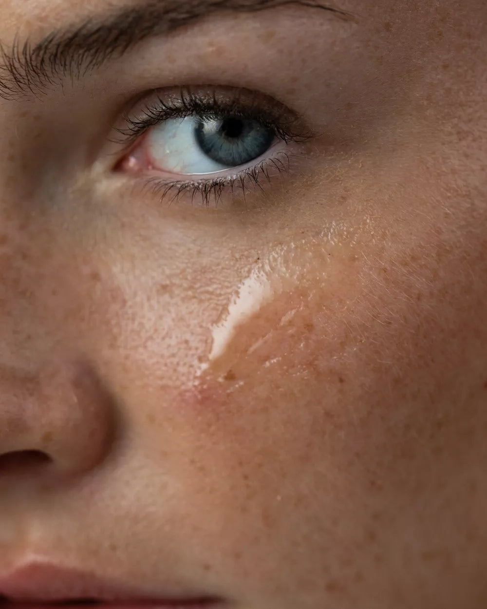 Close-up of skin beneath the eye with a sheer, clear formula applied.